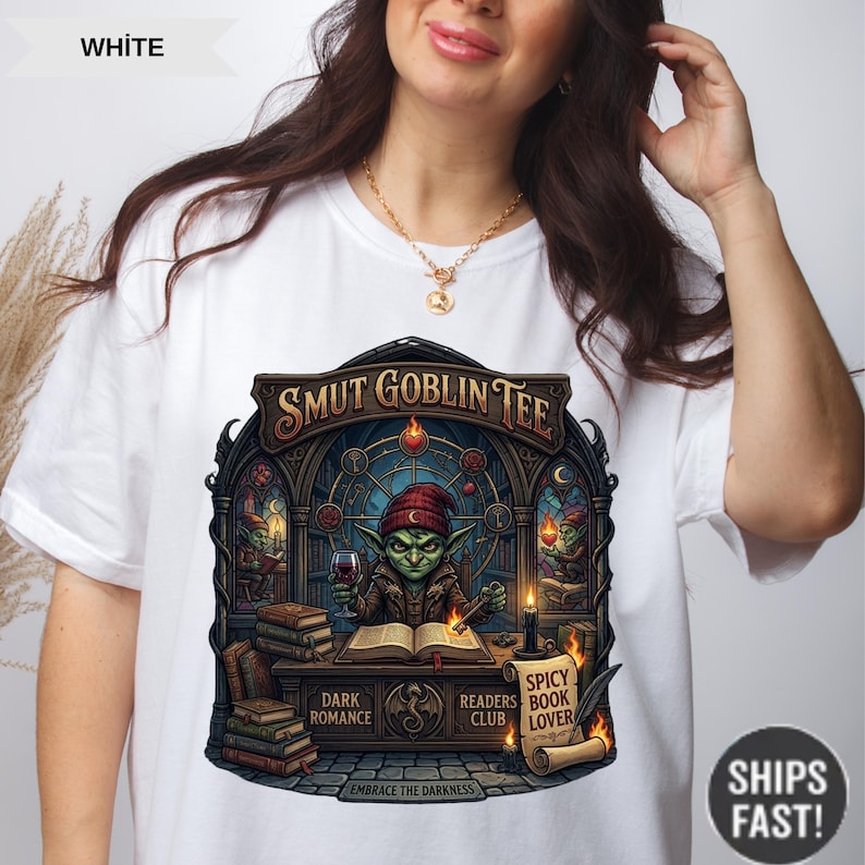 May include: White t-shirt featuring a detailed illustration of a goblin reading a book and holding a glass of wine. The design includes the text "SMUT GOBLIN TEE", "DARK ROMANCE", "READERS CLUB", and "SPICY BOOK LOVER".