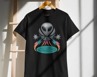 May include: Black t-shirt featuring a unique graphic design. The design includes a silver alien head combined with a basketball, with colorful streaks and a basketball court below. The shirt is hanging on a wooden hanger.