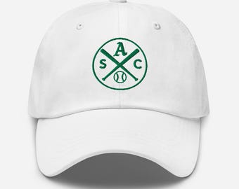 May include: White baseball cap with a curved brim. The cap features a green circular logo with the letters "S", "A", and "C" around crossed baseball bats and a baseball in the center. The cap is made of a soft material.