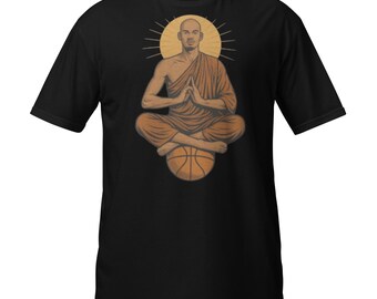 May include: Black t-shirt featuring a graphic of a person in a monk's robe, seated in a meditative pose atop a basketball. The design includes a halo and is rendered in shades of brown and tan.