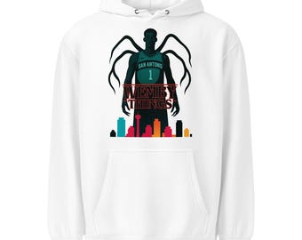 May include: White hoodie featuring a graphic of a basketball player with a San Antonio jersey, number 1. The design includes the text "Wemby Things" and a cityscape silhouette in the bottom. The hoodie has a front pocket and a hood.