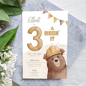 May include: A rectangular birthday invitation card featuring a brown bear wearing a yellow construction hat, a large number 3, and the text Elliot is 3 & Diggin' It. The card includes event details for Saturday, 30th November, from 3pm to 5pm.