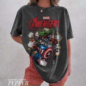 Pu&ograve; includere: Una t-shirt a maniche corte grigio antracite con una stampa grafica dei personaggi Marvel Avengers, tra cui Hulk, Captain America e Iron Man. Il testo Marvel Avengers &egrave; stampato in rosso e bianco sopra l'illustrazione a fumetti.