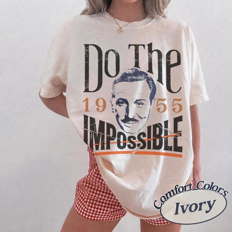 Pu&ograve; includere: T-shirt color avorio con la scritta "Do The Impossible" e un ritratto vintage. I numeri "1955" sono stampati sulla maglietta. La maglietta &egrave; abbinata a pantaloncini a scacchi rossi e bianchi.