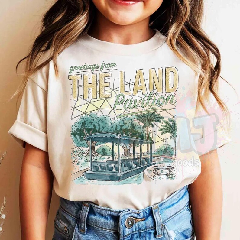 Puede incluir: Una camiseta de color crema con un estampado gr&aacute;fico que incluye el texto "greetings from THE LAND Pavilion". El dise&ntilde;o presenta una ilustraci&oacute;n estilizada de un barco en un canal, palmeras y una estructura de c&uacute;pula geom&eacute;trica en tonos apagados.