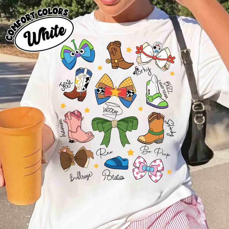 May include: White t-shirt featuring cartoon bow and boot designs with character names like Woody, Buzz Lightyear, and Bo Peep. The shirt includes the text "COMFORT COLORS" and "White" in a circular design.