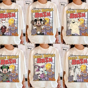 Op de afbeelding: Crèmekleurige T-shirts met een Disney "Oogie Boogie Bash" afbeelding. Elk shirt heeft een ander personage uit de film, een kasteel, pompoenen en de tekst "Oogie Boogie Bash".