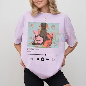 May include: A light purple t-shirt featuring a graphic print of a stone dragon statue surrounded by pink cherry blossoms. Below the image, a music player interface displays the text REFLECTION, Mulan, and a progress bar from 1:40 to 3:15.