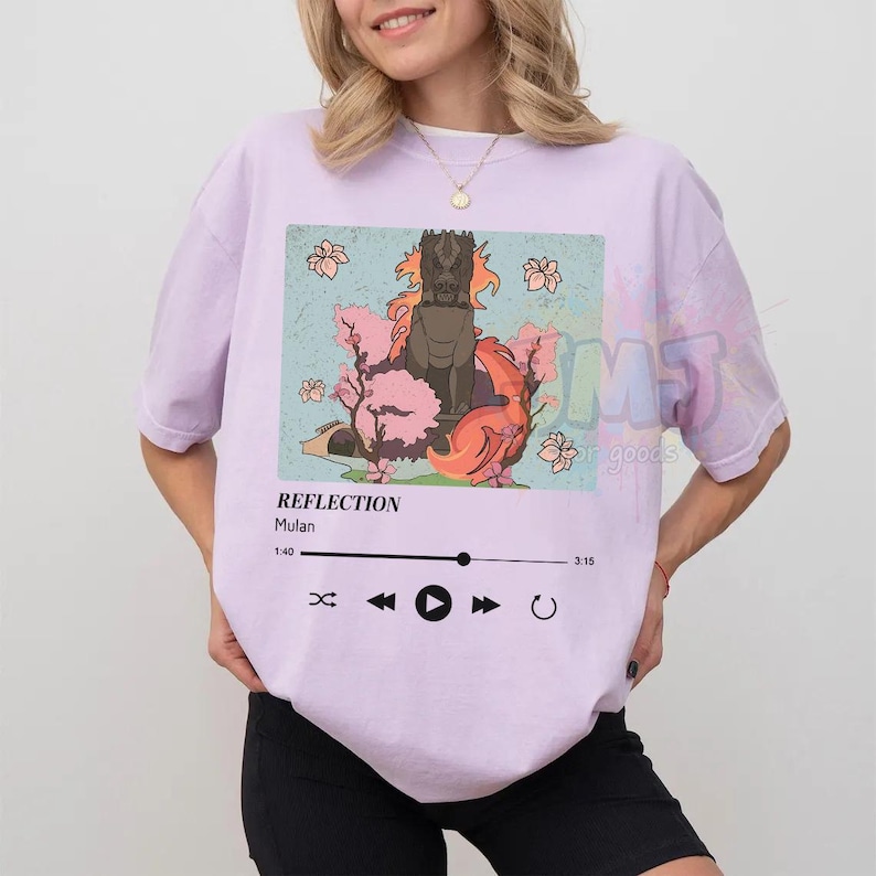 May include: A light purple t-shirt featuring a graphic print of a stone dragon statue surrounded by pink cherry blossoms. Below the image, a music player interface displays the text REFLECTION, Mulan, and a progress bar from 1:40 to 3:15.