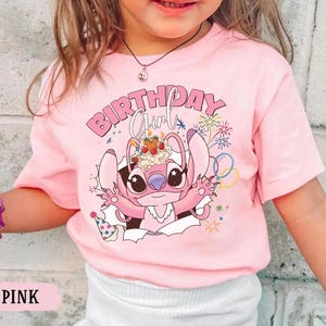 K&ouml;nnte beinhalten: Rosafarbenes T-Shirt mit einer Cartoonfigur und dem Schriftzug "BIRTHDAY Girl". Die Figur ist rosa und h&auml;lt einen Kuchen. Das Design enth&auml;lt auch Feuerwerk und Luftballons.