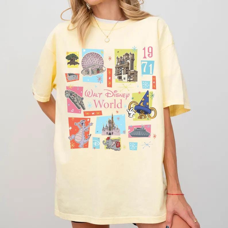 May include: A light yellow t-shirt featuring a colorful collage of Walt Disney World icons and the text "Walt Disney World" and "1971". The design includes images of the Spaceship Earth, Tower of Terror, and other park attractions.