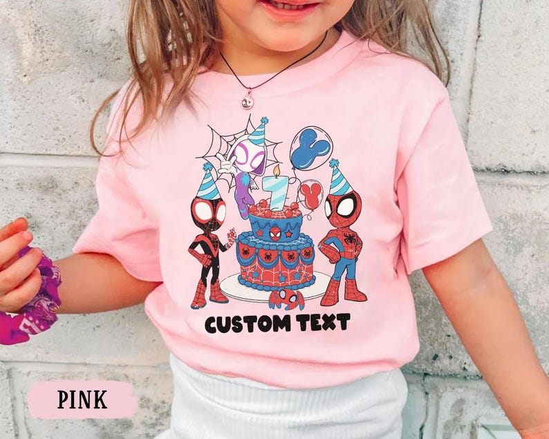 Op de afbeelding: Roze T-shirt met een verjaardagstaart met het nummer 7 en Spider-Man-personages. Het shirt heeft de tekst "CUSTOM TEXT" onder de taart. Het shirt is roze.