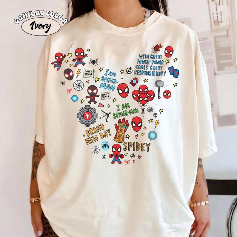 Puede incluir: Camiseta marfil Comfort Colors con un dise&ntilde;o de Spider-Man en forma de coraz&oacute;n. El dise&ntilde;o incluye ilustraciones de Spider-Man, estrellas y frases como "I AM SPIDER-MAN" y "WITH GREAT POWER COMES GREAT RESPONSIBILITY".