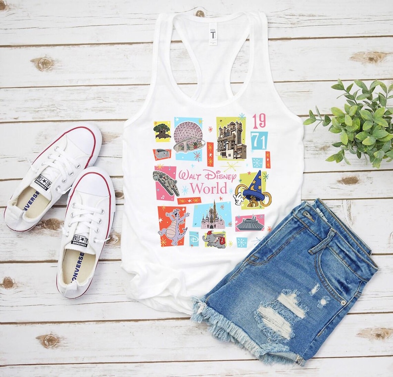 May include: White tank top with a colorful graphic featuring various Walt Disney World icons and the text "Walt Disney World" and "1971". The image also includes denim shorts and white sneakers.