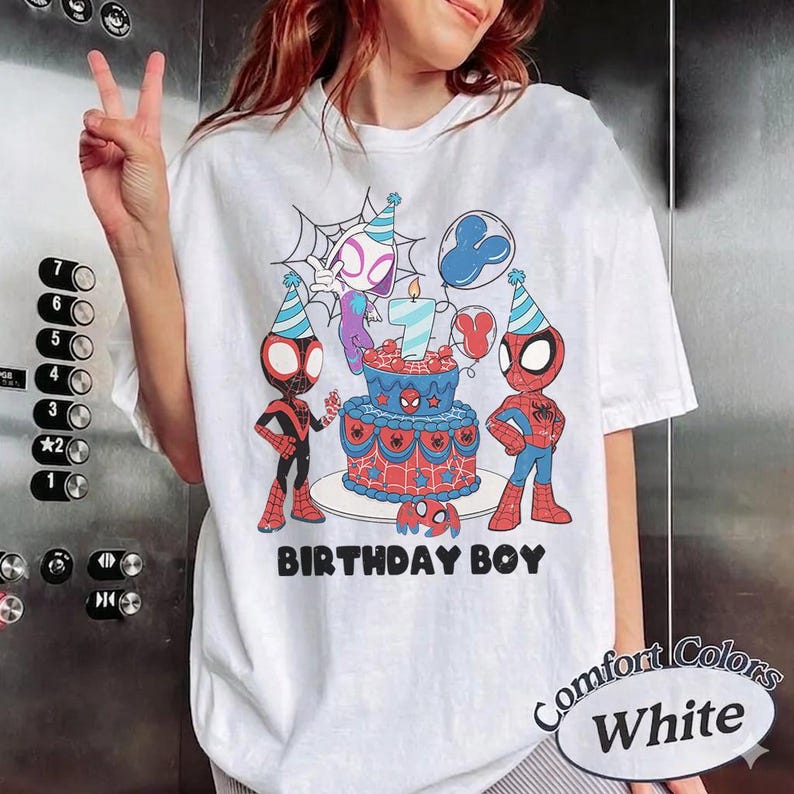 Op de afbeelding: Wit T-shirt met een kleurrijke afbeelding van Spider-Man-personages, een verjaardagstaart en de tekst "BIRTHDAY BOY". Het ontwerp bevat een Spider-Man-logo en een kaars met nummer 7. Het shirt heeft ook de tekst "Comfort Colors White".