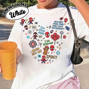 Puede incluir: Camiseta blanca con un dise&ntilde;o de Spider-Man en forma de coraz&oacute;n. El dise&ntilde;o incluye ilustraciones de Spider-Man, estrellas y frases como "I AM SPIDER-MAN" y "BRAND NEW DAY". La camiseta tambi&eacute;n tiene las palabras "COMFORT COLORS" y "White".