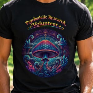 Peut inclure: T-shirt noir avec un motif de champignon psychédélique coloré et le texte "Psychedelic Research Volunteer". Le design présente des couleurs vives, notamment du bleu, du violet et du rose, dans un motif circulaire.