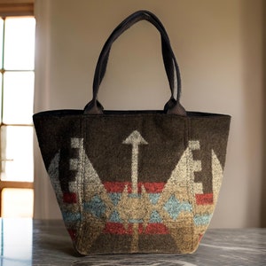 May include: A brown tote bag with a geometric pattern in shades of brown, white, red, and blue. The bag has two black handles.
