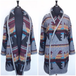 May include: A grey cardigan with a colourful geometric pattern. The cardigan has a shawl collar and long sleeves.