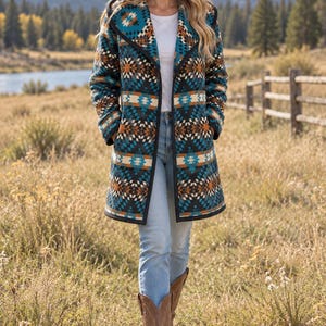 May include: A long-sleeved hooded coat featuring a geometric pattern in shades of teal, black, white, and burnt orange. The coat has a black trim along the front opening and hem, worn over a white t-shirt, light blue denim jeans, and brown boots.