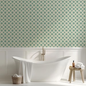 May include: A bathroom scene featuring a white, freestanding bathtub with a white towel draped over the side. A small wooden stool holds rolled white towels and a brown bottle. The wall is covered in a green and cream geometric pattern.