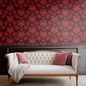 Peut inclure: Scène de salon avec un canapé blanc capitonné avec des bordures en bois, orné de coussins roses et d'une couverture grise claire. L'arrière-plan est un mur avec un papier peint floral rouge foncé.