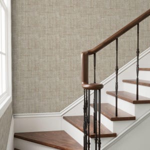 May include: A staircase with wooden steps and a dark brown handrail. The wall is covered in vertical striped wallpaper in shades of beige and brown. The stairs have white risers and a white baseboard.