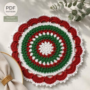 May include: A round crochet doily featuring a central white starburst pattern surrounded by concentric rings of green and red yarn. The outer edge is finished with a scalloped red border trimmed in white. Text reads PDF PATTERN INSTANT DOWNLOAD.