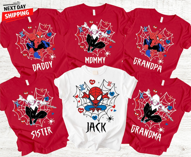 Op de afbeelding: Rode en witte t-shirts met Spider-Man en Spider-Gwen ontwerpen. De shirts zijn gelabeld met "Daddy", "Mommy", "Grandpa", "Sister", "Jack" en "Grandma". De shirts hebben een spinnenwebontwerp met harten en spinnen.