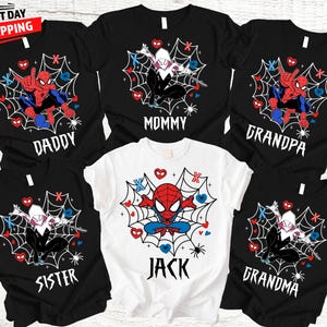 Op de afbeelding: Zwarte en witte t-shirts met Spider-Man en Spider-Gwen ontwerpen, samen met de woorden "Daddy", "Mommy", "Grandpa", "Sister", "Jack" en "Grandma". De shirts hebben een webdesign met harten en spinnen.