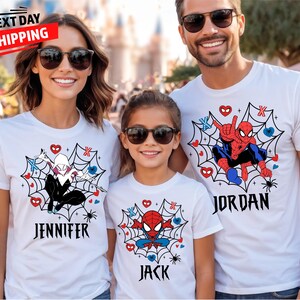 Op de afbeelding: Drie mensen dragen witte t-shirts met superheldenontwerpen. De shirts hebben Spider-Man- en Spider-Gwen-graphics in een spinnenwebontwerp, met namen eronder. De afbeelding bevat de tekst "NEXT DAY SHIPPING".