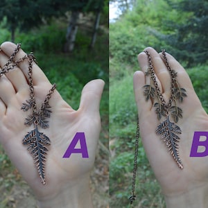 2 photos of slightly different leaf necklaces: pic A shows a large fern leaf on a copper chain, with 4 small fern leaves - 2 hanging from the chain on each side. Pic B has the same fern leaf, with 4 different small leaves, and 2 stars above.