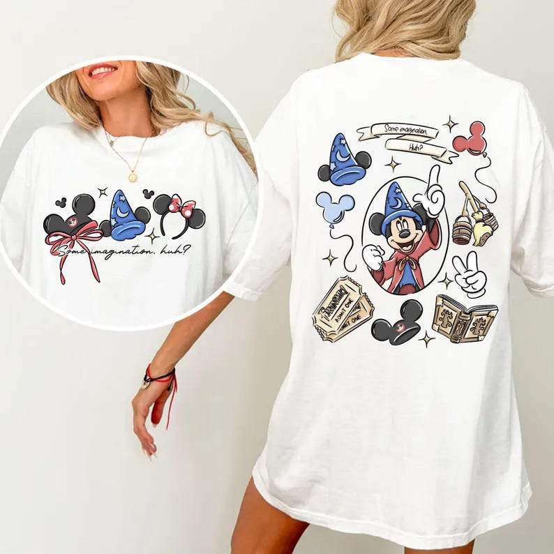 K&ouml;nnte beinhalten: Wei&szlig;es T-Shirt mit Mickey Mouse-Motiven. Auf der Vorderseite sind Mickey Mouse-Ohren mit Schleifen und ein Zauberhut sowie der Text "some imagination, huh?" zu sehen. Auf der R&uuml;ckseite sind Mickey als Zauberer, ein Ticket und andere thematische Elemente abgebildet.