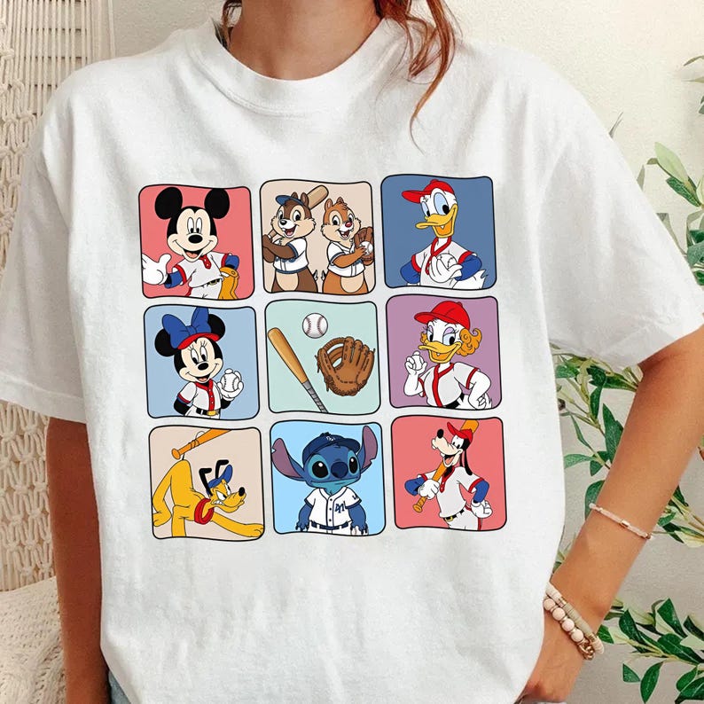 May include: White t-shirt featuring a grid of cartoon characters in baseball uniforms. Mickey Mouse, Chip and Dale, Donald Duck, Minnie Mouse, a baseball, glove, Daisy Duck, Pluto, and Stitch are depicted in colorful squares.