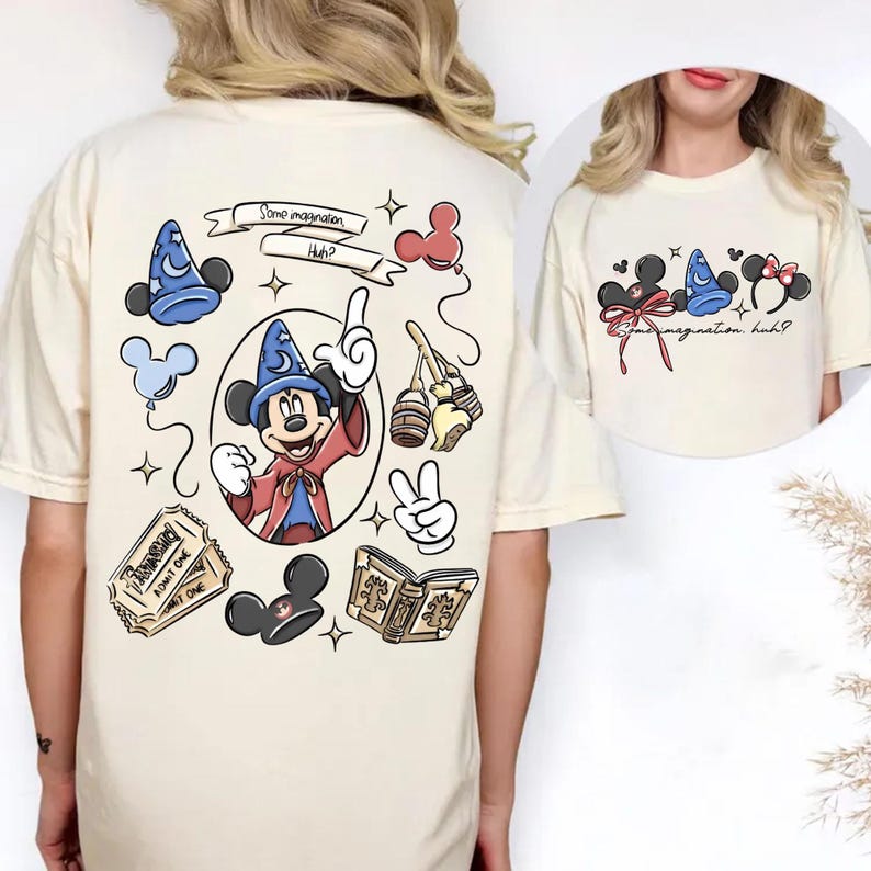 K&ouml;nnte beinhalten: Cremefarbenes T-Shirt mit einem skurrilen Mickey Mouse-Design. Die Grafik zeigt Mickey mit Zauberhut, Tickets, einem Buch und dem Text "Some imagination. Huh?" Ein kleineres Bild rechts zeigt Mickey- und Minnie-Maus-Ohren.