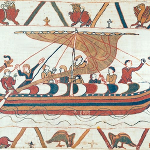 Può includere: Un dettaglio di un arazzo storico raffigurante una nave lunga con una vela e diverse figure. La barca è rossa, blu e bianca, con figure in tuniche di vari colori. Sopra, figure decorative di animali e croci. La scena è ambientata su uno sfondo color crema.