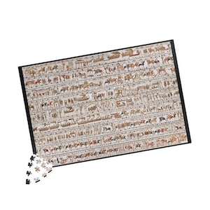 May include: A rectangular jigsaw puzzle with a black border, featuring a detailed ancient Egyptian scene. The puzzle depicts rows of figures, boats, and animals in shades of beige, brown, and red. A few puzzle pieces are separate.