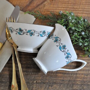May include: Two white ceramic bowls with a blue and black floral design. The bowls are on a wooden surface.