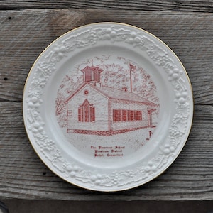 May include: White ceramic plate with a gold rim and a red illustration of a schoolhouse. The text on the plate reads "The Plantree School, Plantree District, Bethel, Connecticut."