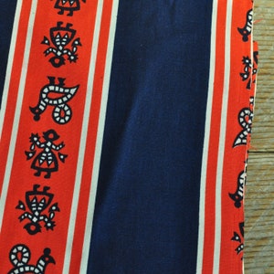 May include: Red and white striped fabric with a dark blue stripe in the center. The fabric has a repeating pattern of black stylized figures.