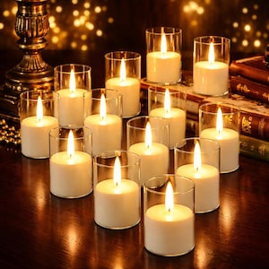 Könnte beinhalten: Eine Anordnung von brennenden, weißen Säulenkerzen in transparenten Glashaltern. Die Kerzen stehen auf einer dunklen Holzoberfläche und erzeugen ein warmes Ambiente. Der Hintergrund zeigt unscharfe Lichter und antike Bücher.