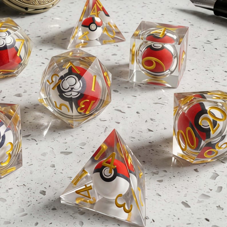 May include: A set of clear polyhedral dice featuring miniature red and white spherical balls inside each piece. The dice have gold-colored numbers etched on the exterior surfaces, including a four-sided pyramid die and a twenty-sided die.