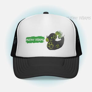 May include: Black and white trucker hat with a black bill and mesh back. The front features a black duck design with yellow accents and green feathers, along with the text "MUTINY FARMS" in green.