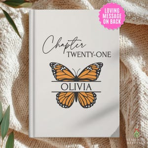 May include: A white hardcover book featuring the text Chapter TWENTY-ONE in black, centered above a graphic of an orange and black monarch butterfly. The name OLIVIA is printed in black inside a horizontal line across the butterfly's wings.