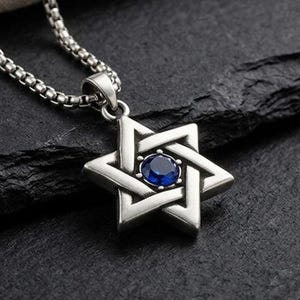 May include: A silver-toned Star of David pendant necklace featuring a round, deep blue gemstone set in the center. The pendant hangs from a matching silver-toned box chain, showcasing a polished metallic finish and a geometric six-pointed star design.