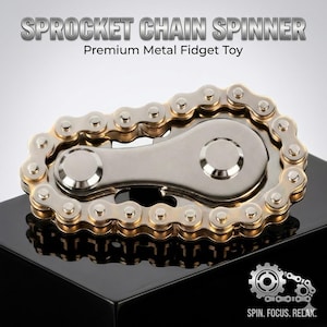 Peut inclure: Un hand spinner en métal argenté et doré en forme de chaîne de vélo. Le texte "SPROCKET CHAIN SPINNER" et "Premium Metal Fidget Toy" sont affichés. Un logo d'engrenage avec le texte "SPIN. FOCUS. RELAX." est en bas à droite.