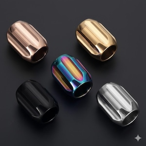 May include: An assortment of six metal beads in various colors, including bronze, gold, black, silver, and iridescent. Each bead has a cylindrical shape with vertical grooves, and a hole through the center.