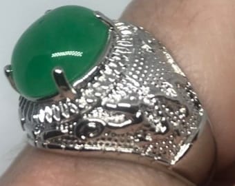 May include: A silver ring with an oval green gemstone set in a detailed design.