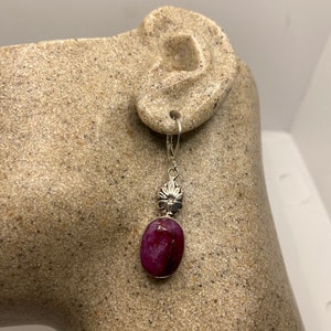 Puede incluir: Pendientes de plata con una piedra ovalada rosa y un dije de flor de plata.