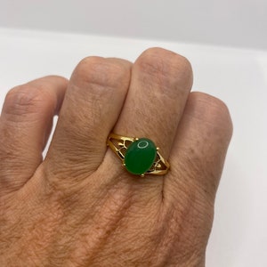 May include: A gold ring with a green oval gemstone set in a delicate filigree design.